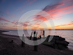 Remains of old wooden jetty looking to Harwich with stunning sunset, Felixstowe