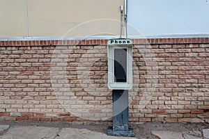 Remains of a pay telephone booth against brick wall in New Mexico