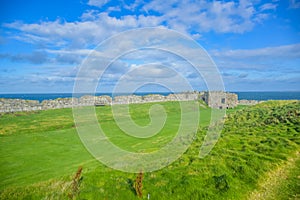 Remains of Peel Castle wall at Peel hill covered with green grass in Isle of Man