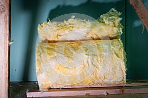The remains of a roll of glass wool at a construction site close-up. Yellow mineral wool on the floor against the background of