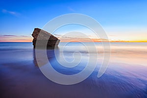 Remains of the watchtower on the shore of the beach at sunset