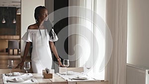 Remarkably beautiful african american female fashion model waiting for somebody in restaurant with white interior