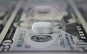 Remdesivir pill on top of 50 dollar banknote. Concept photo. Illustrative for potential profit from COVID-19 treatment drug.