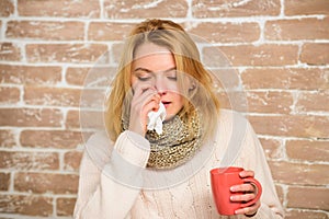 Remedies should help beat cold fast. Woman feels badly ill sneezing. Girl in scarf hold tea mug and tissue. Runny nose