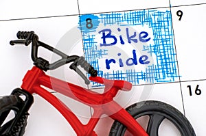 Reminder bike ride in calendar with red bicycle toy.