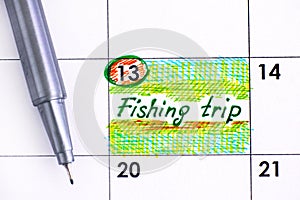 Reminder Fishing Trip in calendar with pen.