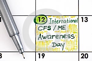 Reminder International CFS/ ME Awareness Day in calendar with pen photo