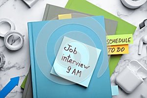 Reminder note about job interview and stationery on table