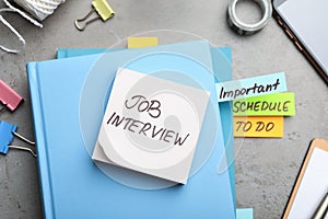 Reminder note about job interview and stationery on table