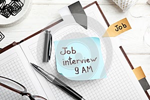 Reminder note about job interview and stationery on table