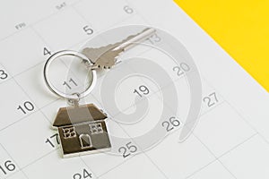 Reminder to pay for mortgage, schedule event or real estate payment day, silver house keyring on white clean calendar, yellow