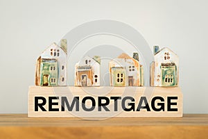 REMORTGAGE, a word written on a wooden block with miniature houses. Real estate business and financial concept, copy space photo