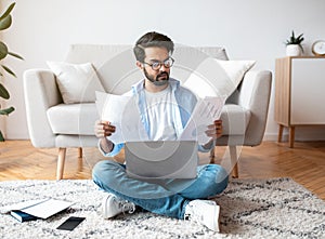 Remote Business. Busy Arab Man Working With Papers And Laptop At Home