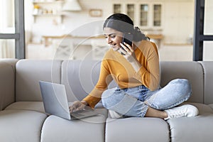 Remote Business. Indian Woman Talking On Phone And Using Laptop At Home