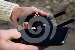 Remote control and smartphone in male hands. A man holding a transmitter and piloting some vehicles. A drone, radio controlled car