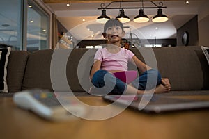 Remote control and tablet on table against girl