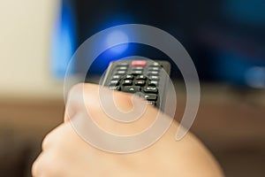 Remote control woman hand. Background blur tv