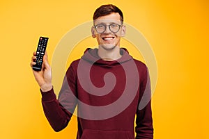 Remote controlled man. cheerful man holding a remote control in his hand and looking at the camera