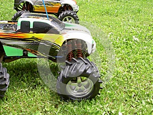 Remote-controlled models of off-road cars standing in a meadow overgrown with grass, view close-up