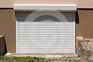 Remote controlled new modern white outdoor garage roll up doors mounted on newly built suburban family house side wall