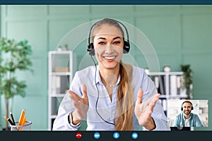 Remote distant communication. Young woman in headphones having video call with her colleague, talking at webcamera