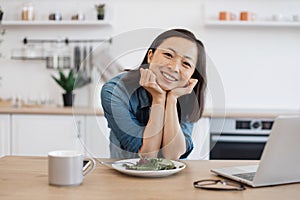 Remote employee sitting at table with laptop and salad