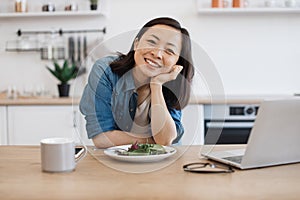 Remote employee sitting at table with laptop and salad