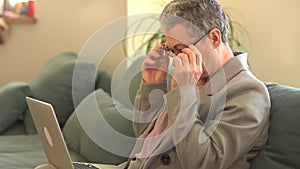 Remote employment, a female freelancer with a gray short haircut looks at the camera working with a laptop while sitting