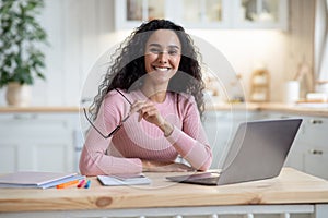 Remote Entrepreneurship. Happy Millennial Woman Sitting At Table With Laptop In Kitchen