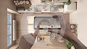 Remote home control system on a digital smart phone tablet. Device with app icons. Interior of country kitchen with table in the