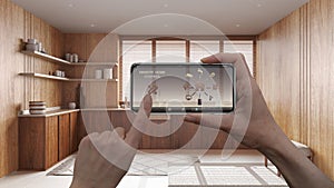 Remote home control system on a digital smart phone tablet. Device with app icons. Interior of japandi wooden kitchen in the