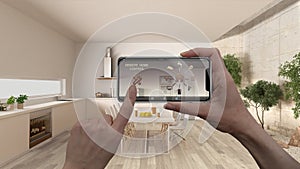 Remote home control system on a digital smart phone tablet. Device with app icons. Interior of minimalist white kitchen in the bac