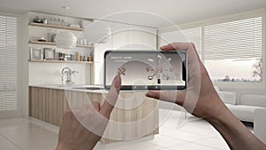 Remote home control system on a digital smart phone tablet. Device with app icons. Interior of modern kitchen with shelves and cab