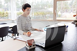 Young woman with blueprint working at home office