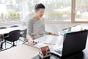 Young woman with blueprint working at home office