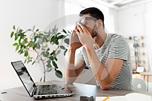 Tired man with laptop working at home office