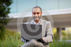 Remote Office. Happy Young Businessman Using Laptop While Sitting Outdoors