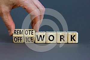 Remote or office work symbol. Businessman turns cubes and changes words `office work` to `remote work`. Beautiful grey backgro