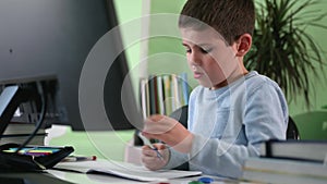 Remote training, a little smart boy learns lessons at home sitting at a computer and watches a video lesson with his