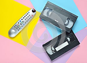 Remote, video cassette on a colored pastel background. Retro entertainment technology from the 80s. Minimalism trend. Top view.