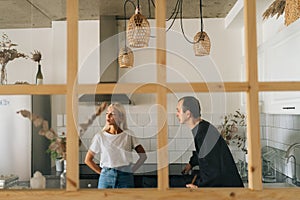 Remote view of angry husband scolding, raising voice, yelling at ignoring young girlfriend wife standing in kitchen room