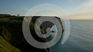 Remote wide shot of beautiful cliffs of Etretat in France on evening at sunset. Scenic view of one most visited