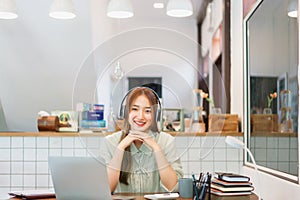 Remote work concept, Woman entrepreneur wears headphone to listening music in coworking space