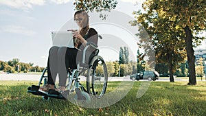 Remote work concept. Young disabled woman in the wheelchair using smartphone and laptop