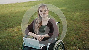 Remote work concept. Young disabled woman in the wheelchair using smartphone and laptop