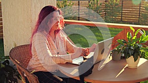 Remote work concept. Young woman working on her computer on a terrace of her house