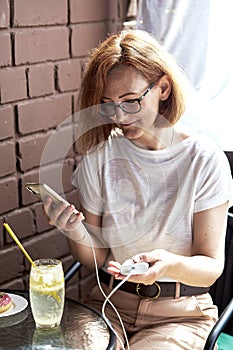 Remote work a freelancer multitasks with her phone and powerbank in a cafe