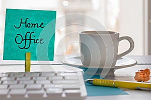 Remote work at home during the Coronavirus epidemic. A card with the words `Home Office` and a cup of coffee, pen, computer keyboa