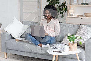 Remote Work. Joyful Black Woman Working On Laptop On Couch At Home