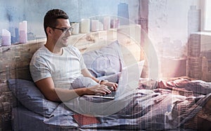 Joyful nice man typing on the laptop